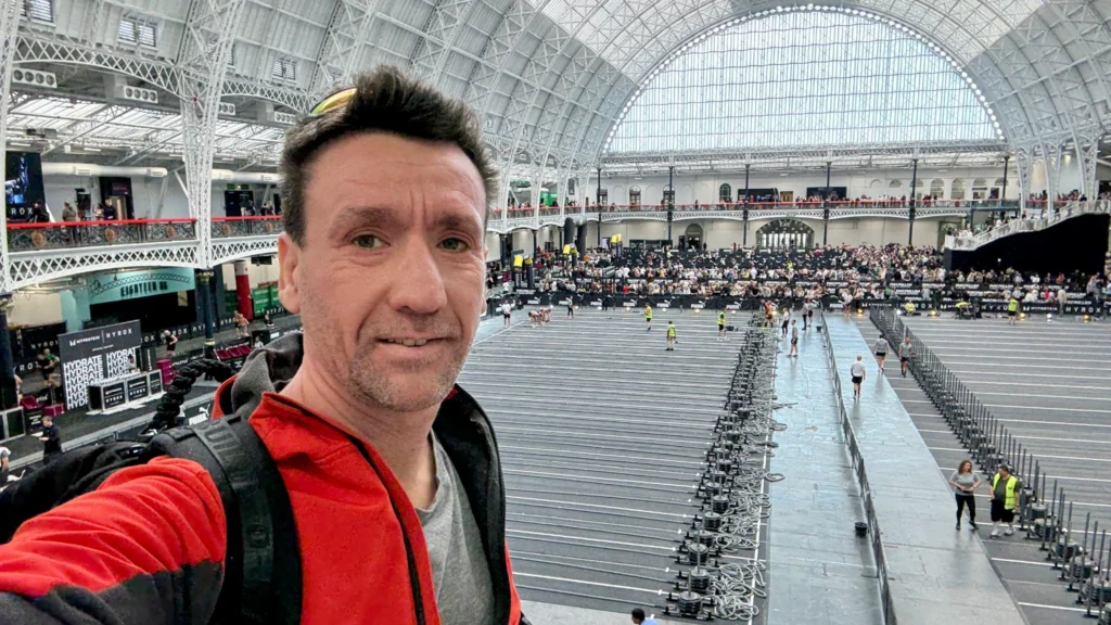 Athlete entering HYROX venue with crowd, banners and lights visible