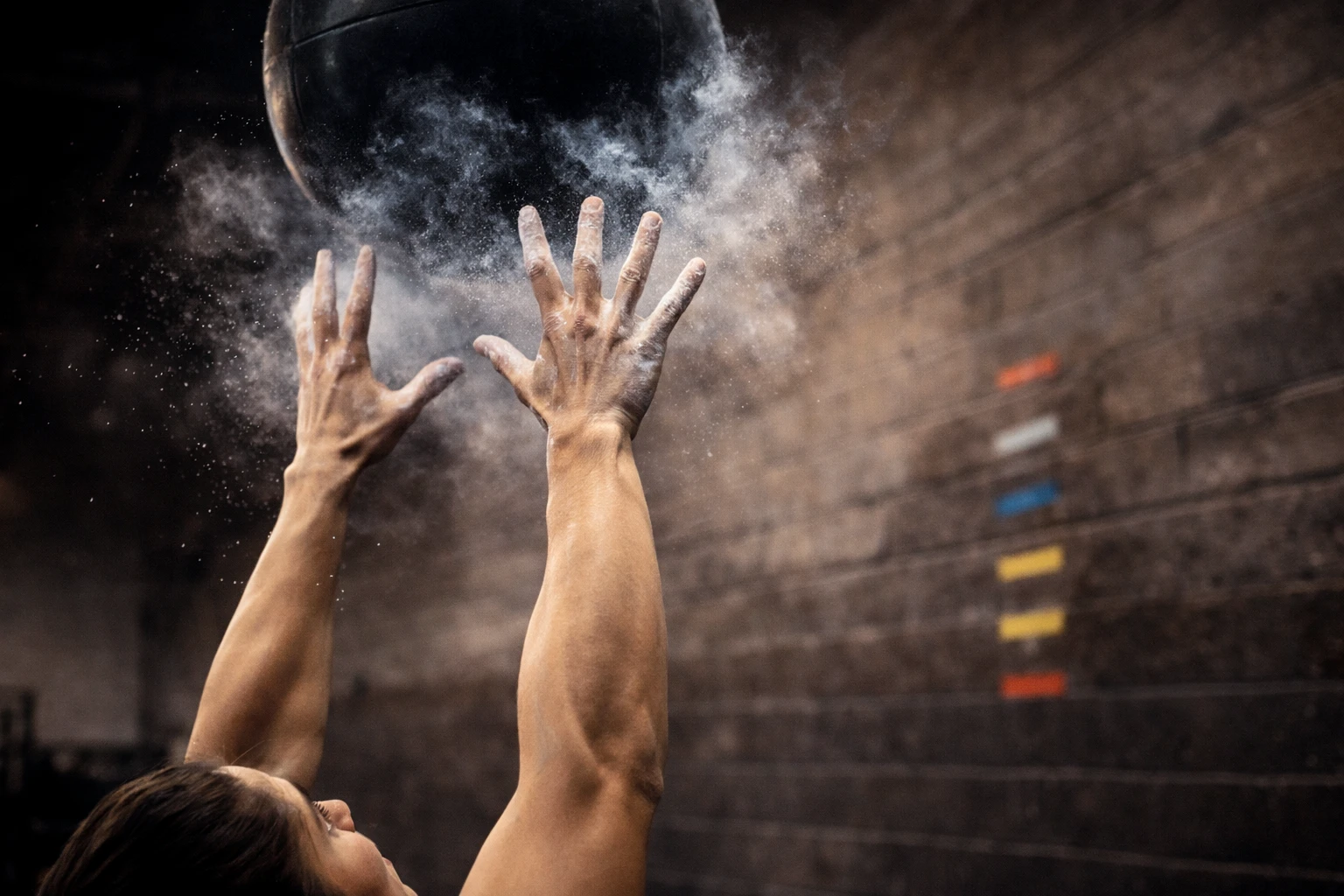 Close-up of hands releasing the ball overhead with focus and chalk dust in motion