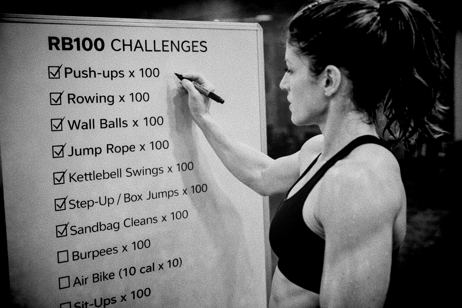 Athlete checking off a whiteboard with 10 RB100 challenges listed and sweat dripping
