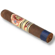 Crowned Heads Broadway Epicure single loose cigar photographed diagonally against a white background, showing its dark brown Connecticut Broadleaf wrapper, ornate red and gold Crowned Heads band, separate Broadway band and dark blue ribbon