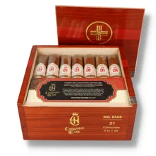 Open polished reddish-brown wooden box of 21 Crowned Heads Mil Días Edmundo cigars, showing seven individually sleeved brown cigars across the front row with ornate cream and gold bands and red Crowned Heads emblems.
