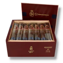 Open burgundy wooden box of 21 Crowned Heads Broadway Epicure cigars, showing individually sleeved cigars with ornate red and gold bands, dark blue foot ribbons, gold Broadway branding inside the lid and Crowned Heads lettering on the front of the box.