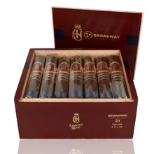 Open burgundy wooden box of 21 Crowned Heads Broadway Epicure cigars, showing individually sleeved cigars with ornate red and gold bands, dark blue foot ribbons, gold Broadway branding inside the lid and Crowned Heads lettering on the front of the box.