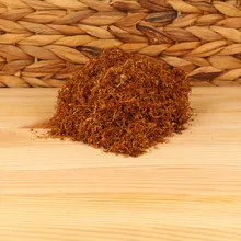 A small pile of fine cut Virginia tobacco on a plank of wood with wicker background