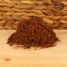 A small pile of light hand rolling tobacco on a wicker and wood background