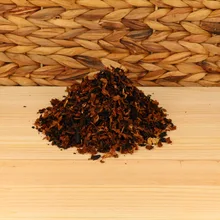 A small pile of pipe tobacco on a wodden base with a wicker background