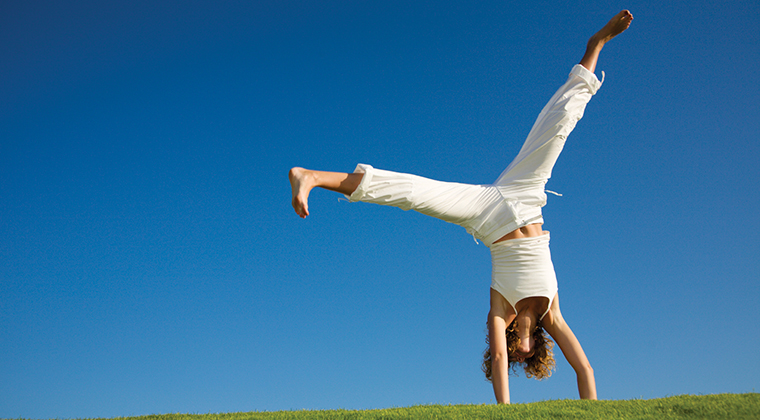 Young woman doing cartwheel on grass