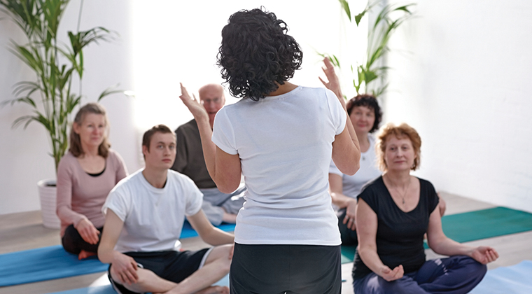 Instructor explaining the benefits of yoga to class