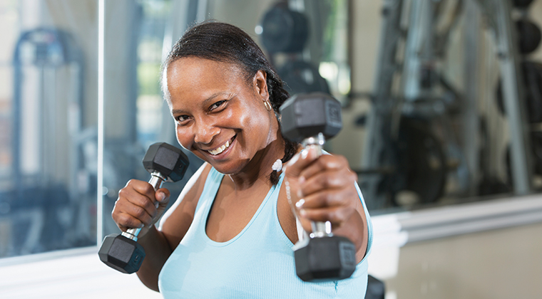 Mature woman in health club, lifting weights.