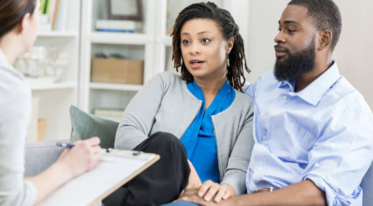 adult couple talk with female counselor about problems in their marriage.
