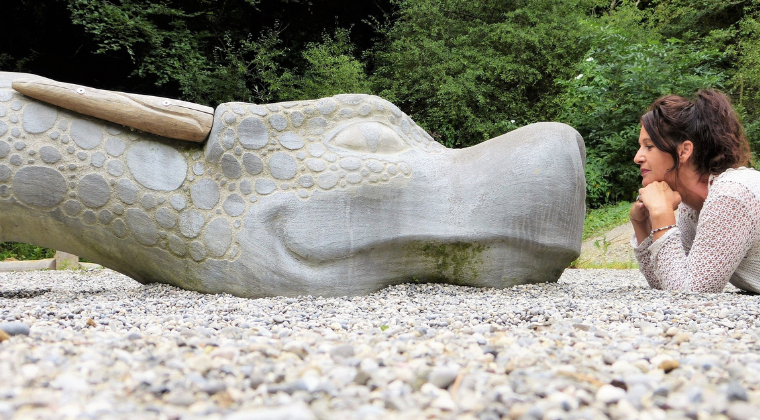 woman laying down, facing stone statue of dragon