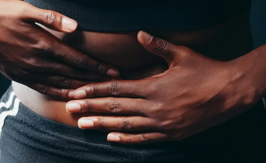 A person holding their stomach depicting Connection Between Stress and Digestive Issues.