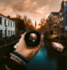 Person's hand holding SLR Lens infront of a sunset scene