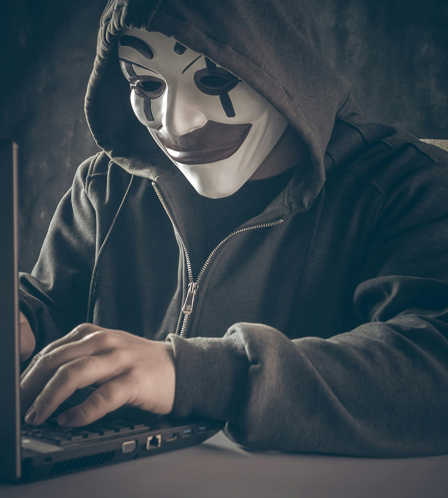man in mask typing on laptop