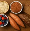 Colorful selection of carbohydrate-rich foods- oats, brown rice, sweet potato, berries, and whole grain bread on a wooden table