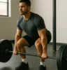 Athlete performing a barbell squat or deadlift in a gym, with focus on full-body engagement and strong posture