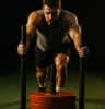 Athlete pushing a sled outdoors on turf or gym floor, with dramatic lighting highlighting effort and muscle engagement