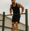 Athlete performing a controlled calisthenics move like a muscle-up, front lever, or handstand push-up outdoors or in a minimal training environment