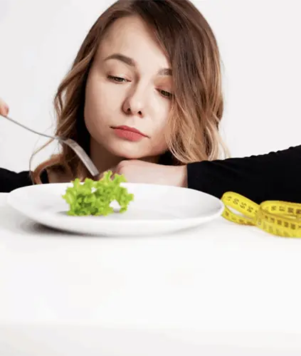 Young woman trying to lose weight, looking at lettuce on a plate