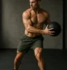 Athlete performing controlled rotational core movement with a medicine ball in a minimalist gym, mid-twist, strong lighting showing oblique engagement