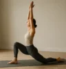 A wellness-focused adult performing a deep lunge with arms overhead, showing dynamic hip mobility and balance