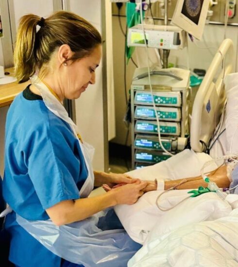 Nurse giving hand massage to elderly patient in intensive care