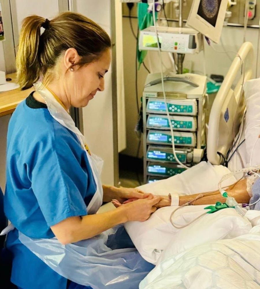 Nurse giving hand massage to elderly patient in intensive care