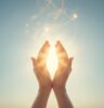 Hands held together with light emanating from the palms upwards