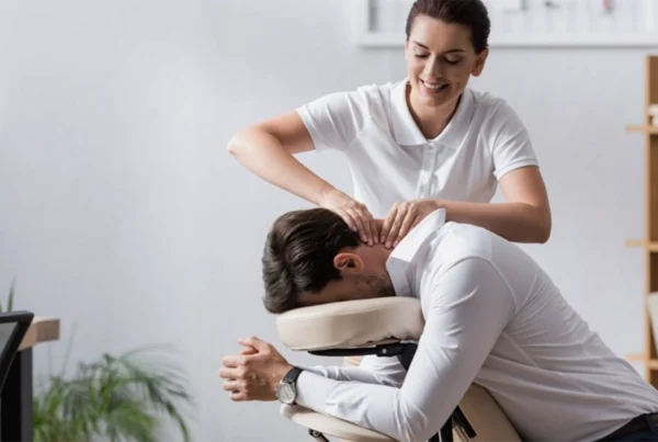 Professional massage therapist giving neck massage to man