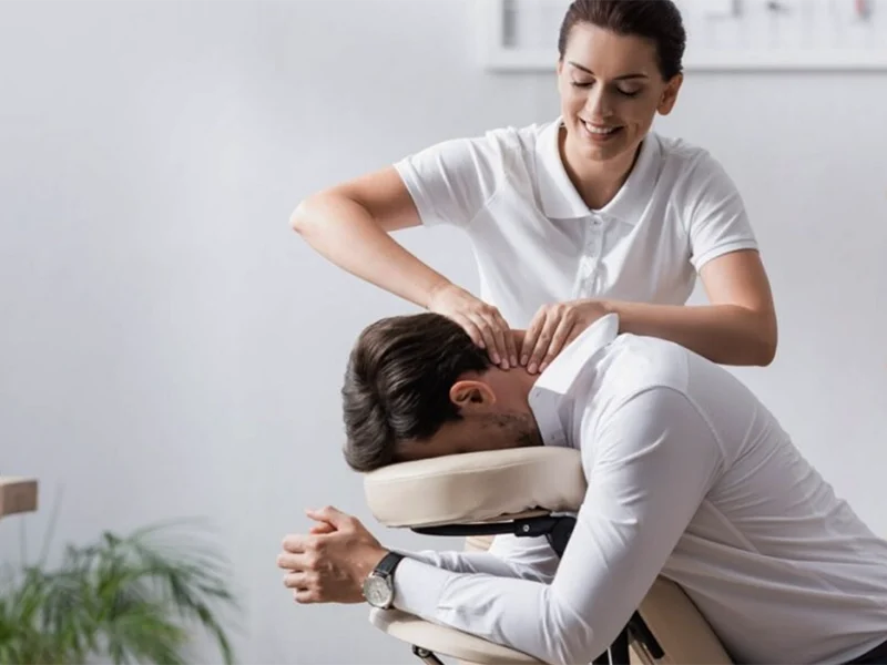 Professional massage therapist giving neck massage to man