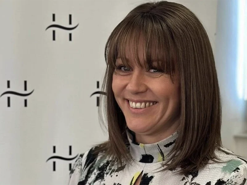Smiling professional woman with brown hair and branded logo background