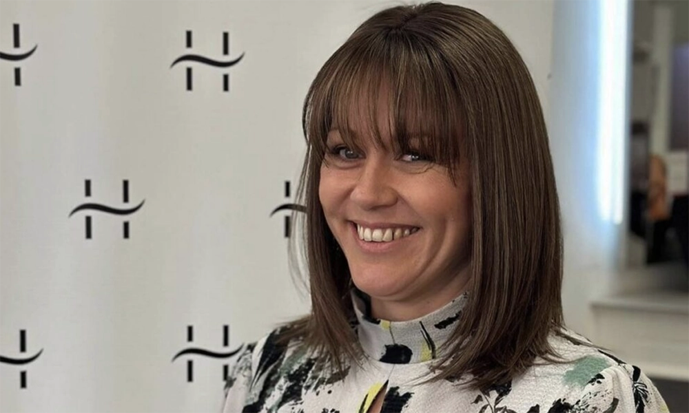 Smiling professional woman with brown hair and branded logo background