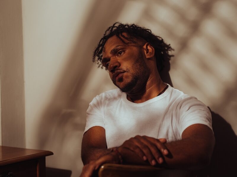 Lonely looking man sitting inside, with distant look in his eyes