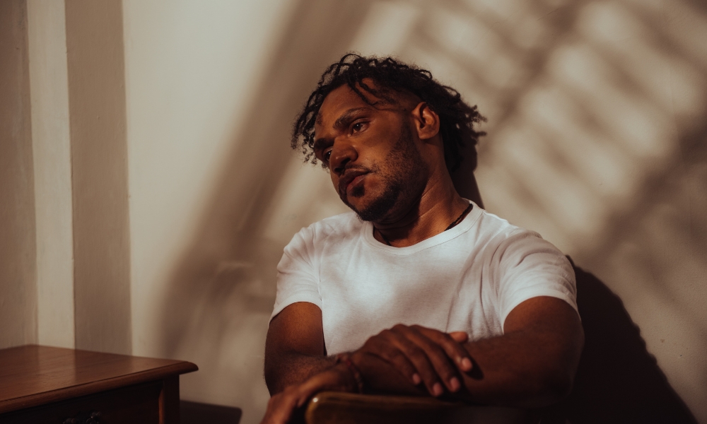 Lonely looking man sitting inside, with distant look in his eyes