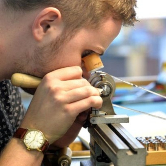 person at watchmakers lathe