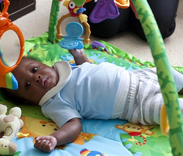 Baby lying on play mat at home looking towards the camera