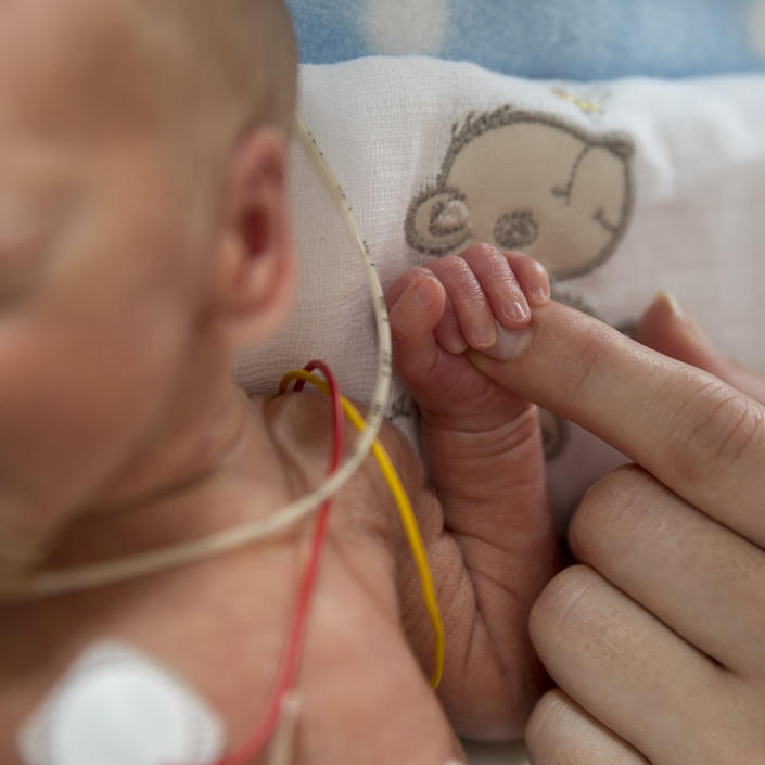 Close up on baby hand gripping onto a parent's finger