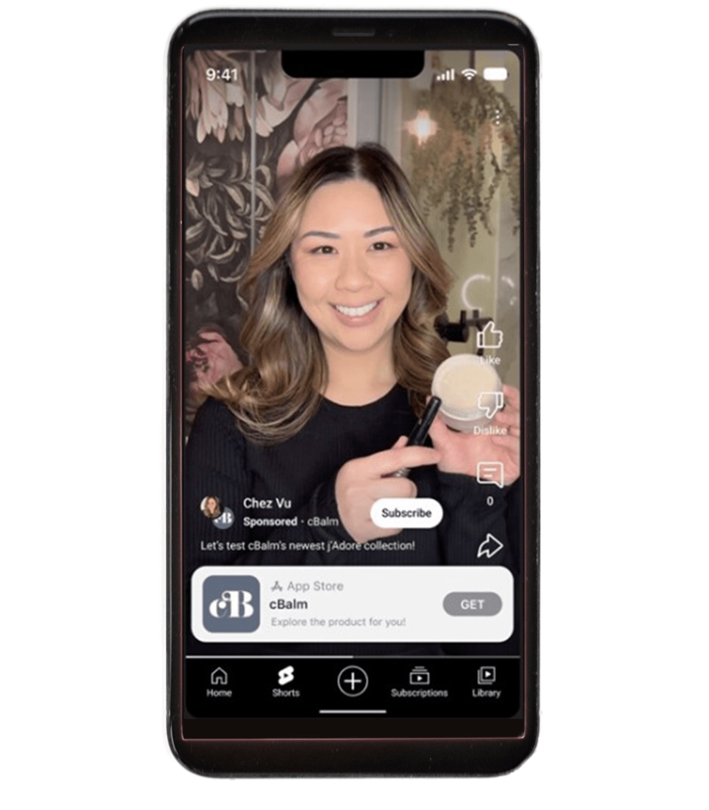 A phone showing a YouTube Short by the creator Chez Vu holding a cosmetics jar, labelled Sponsored and cBalm, with the caption Let's test cBalm's newest Adore collection and an App Store card with a Get button.