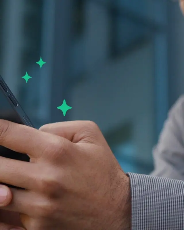 A man smiling at his phone against green