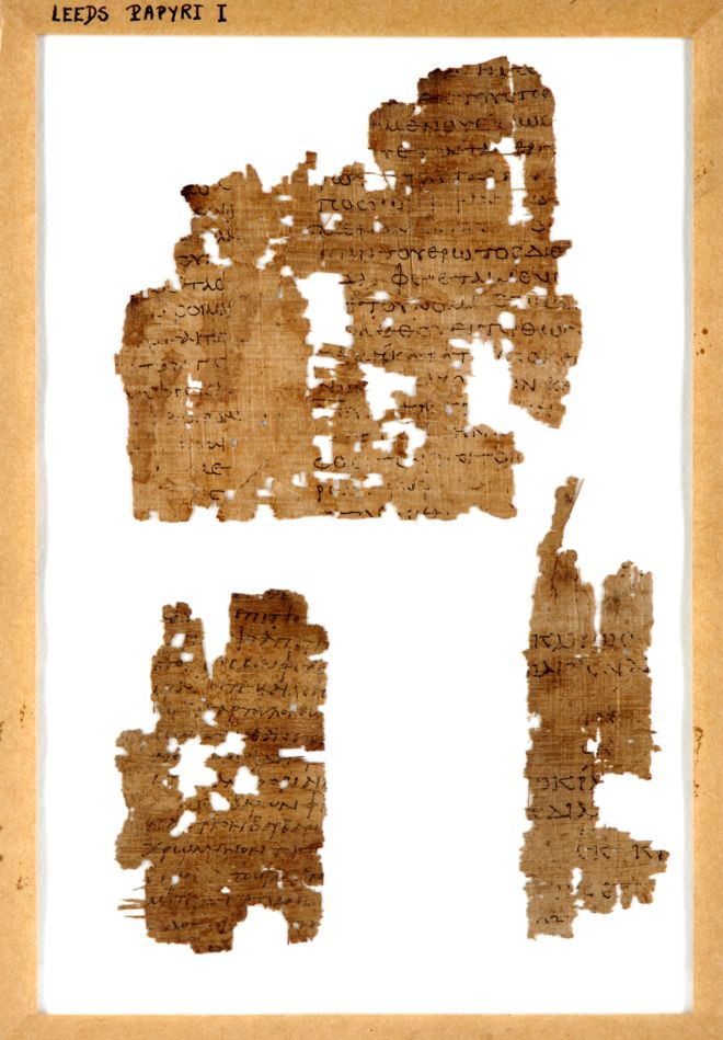 A fragment of papyrus, torn and with holes in it.  The writing is still visible in black ink.