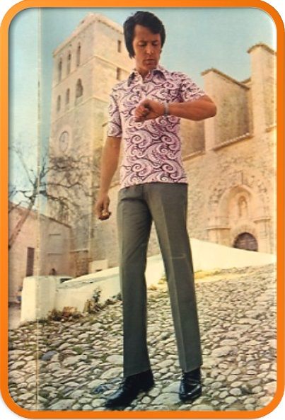 Photo of a man wearing grey trousers and a brightly coloured shirt with swirly patterns