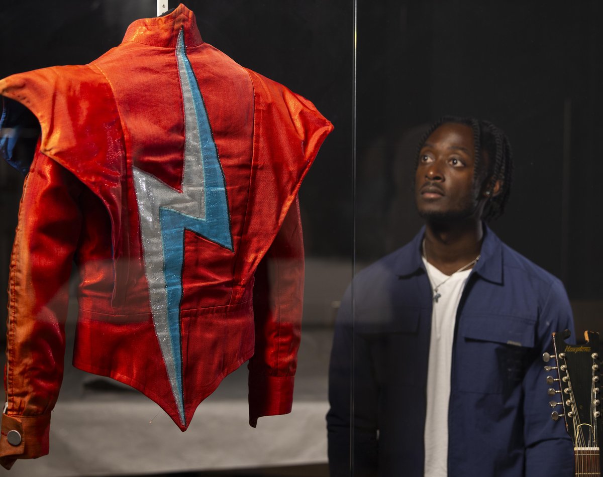A visitor looks at the Aladdin Sane jacket designed by Freddie Burretti for David Bowie on the Ziggy Stardust live tour in 1973