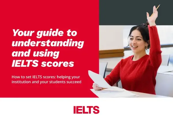 Front cover of the IELTS guide titled “Your Guide to Understanding and Using IELTS Scores.” The cover features a smiling student in a red sweater raising her hand in a classroom, alongside bold red and white text promoting the guide.
