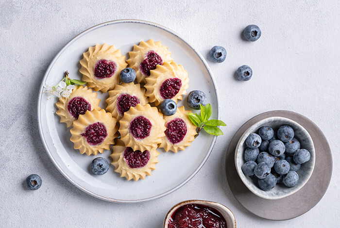 jam drop cookies on a plate with a bowl of fresh blueberries