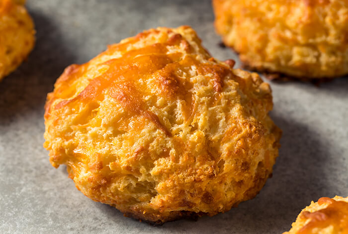golden-brown cheese scones on a parchment-lined baking tray