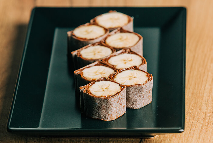 banana sushi rolls sliced and served on a black plate