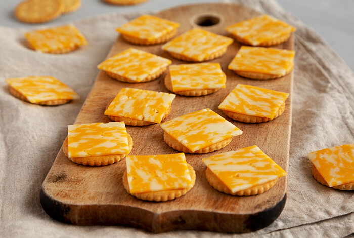 cheddar cheese crackers arranged on a wooden board