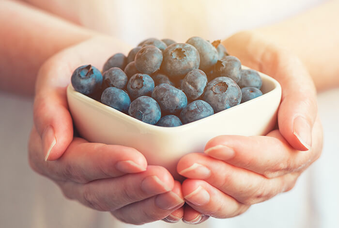 a bowl of fresh blueberries carried in female hands