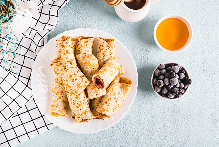 pieces of blueberry roll-ups in a white plate and some fresh blueberries on the side