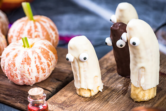 ghost-shaped Halloween dog treats made with yogurt-covered bananas and carob chip eyes
